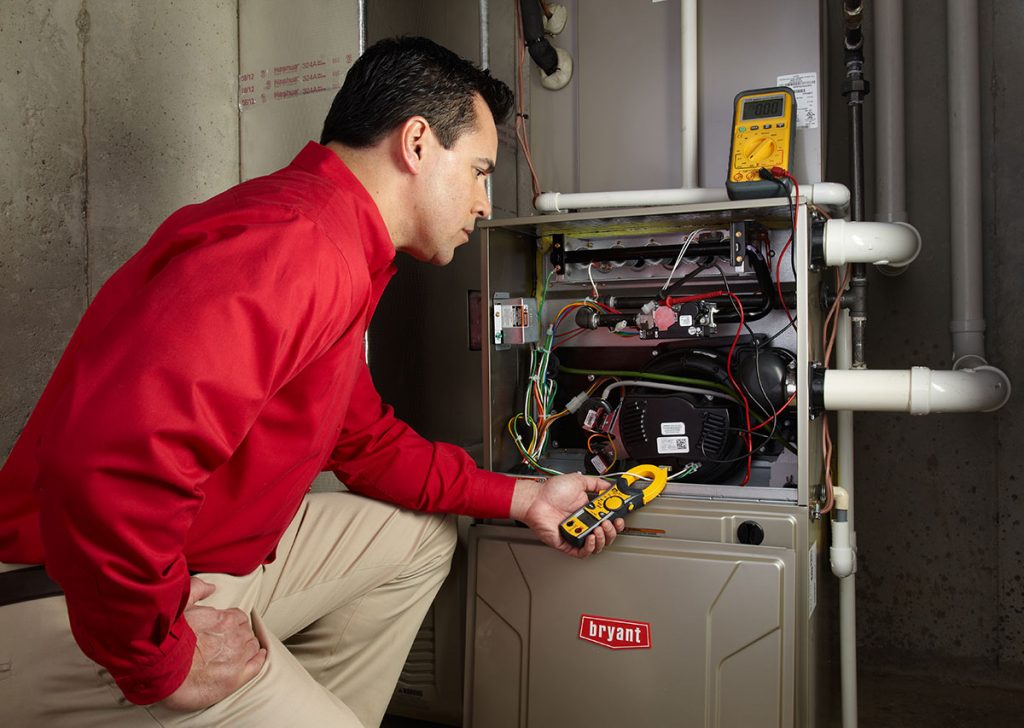 Heating and air conditioning technician servicing an indoor furnace in Layton, UT