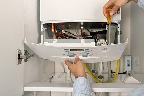 HVAC technician repairing an indoor boiler in Layton
