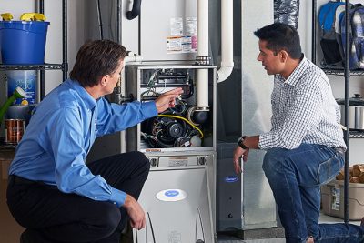 HVAC technician explaining furnace repair and maintenance to a homeowner in Layton, UT