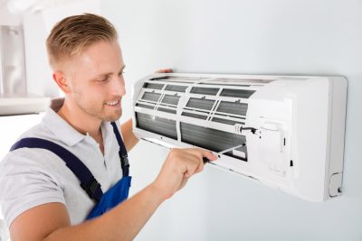 HVAC technician cleaning and repairing a ductless mini split AC in Layton, UT
