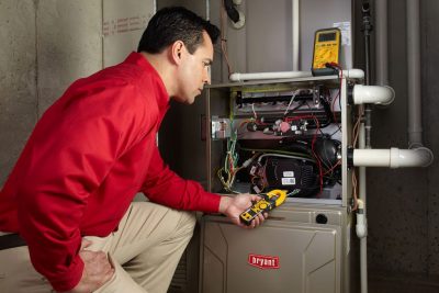 Heating and air conditioning technician servicing an indoor furnace in Layton, UT